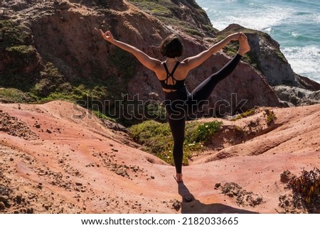 Strong woman stretching and making yoga asana at the sandy beach