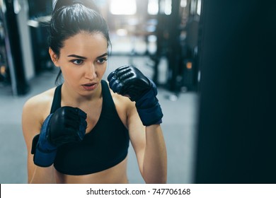 Strong Woman Training And Punching A Bag With Kickboxing Gloves In The Gym Workout. Sport, Fitness, Lifestyle And People Concept. 