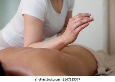 Strong Woman In A White T-shirt Gives A Back Massage To Another Woman With An Elbow