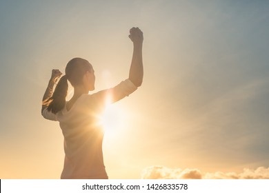 Strong Woman, Winning, Success , And Life Goals Concept. Young Woman With Arms Flexed Facing The Sunset. 