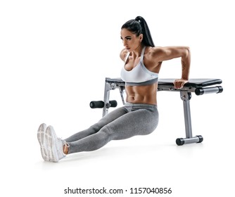 Strong woman working out arms muscles doing triceps dips using bench. Photo of latin woman with perfect body on white  background. Strength and motivation