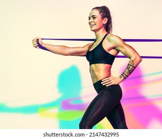 Strong woman working with resistance band. Photo of woman in black sportswear on white background with effect of rgb colors shadows. Sports and healthy lifestyle