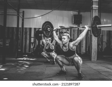 Strong women bodybuilder doing overhead with heavy barbell in modern cross gym. Functional training class. Bodybuilding and Fitness