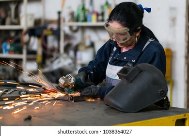 Strong And Worthy Woman Doing Hard Job In Car And Motorcycle Repair Shop. She Using Grinder To Fix Some Metal Bike Parts.