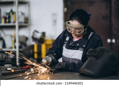 Strong And Worthy Woman Doing Hard Job In Car And Motorcycle Repair Shop. She Using Grinder To Fix Some Metal Bike Parts.