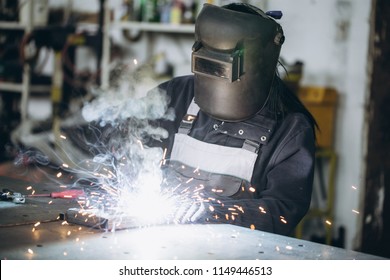 Strong and worthy woman welder doing hard job in car and motorcycle repair shop. She using welding machine to fix some metal bike parts. - Powered by Shutterstock