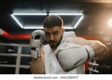 Strong young boxer training with boxing gloves in the gym. A determined young man practices his punching technique during training at a boxing club. - Powered by Shutterstock