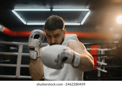 Strong young boxer training with boxing gloves in the gym. A determined young man practices his punching technique during training at a boxing club. - Powered by Shutterstock