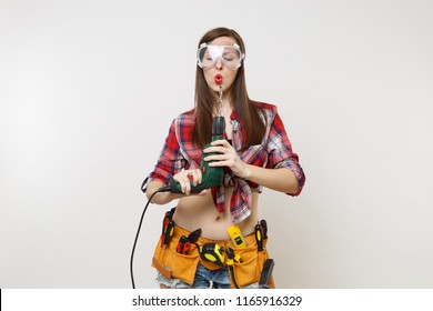 Strong Young Energy Handyman Woman In Plaid Top Shirt Denim Shorts Kit Tools Belt Full Of Instruments In Protective Goggles Hold Power Electric Drill Isolated On White Background. Female In Male Work