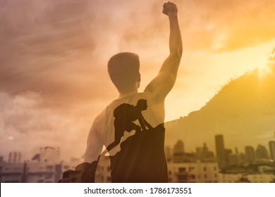 Strong young man in the city with fist in the sky climbing up a mountain. Reaching goals, and feeling motivated concept. Double exposure