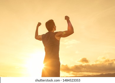 Strong young man flexing his arms to the sunset sky. People victory and inner strength concept.  - Powered by Shutterstock