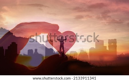 Strong young man on a mountain facing city background feelings of hope, strength, compassion and love
