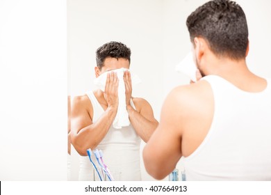 Strong Young Man Using A Towel To Dry His Face After Washing It In The Bathroom In Front Of A Mirror