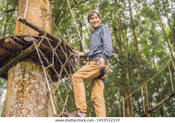 strong\
young men in a rope park on the wood\
background