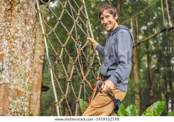 strong
young men in a rope park on the wood
background