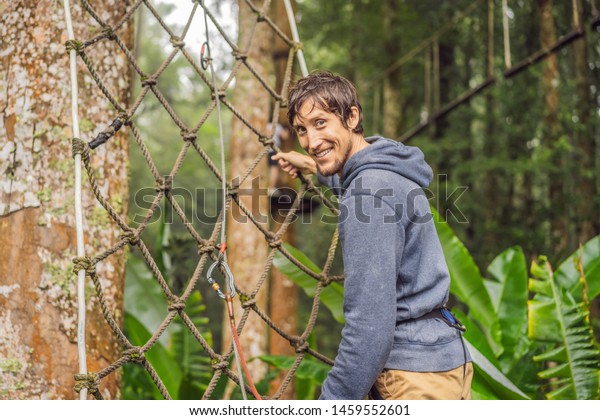 strong\
young men in a rope park on the wood\
background