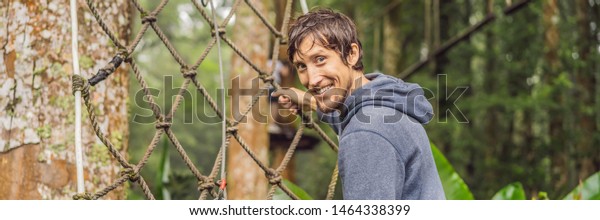 strong young men in a rope park on the wood
background BANNER, LONG
FORMAT