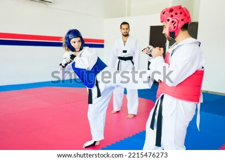Strong young woman with a safety helmet sparring with a man fighter during a karate practice