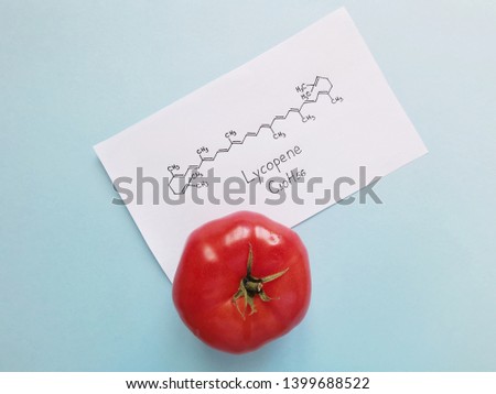 Structural chemical formula of lycopene molecule written on a white sheet of paper with tomato. Lycopene is red tomato pigment molecule.