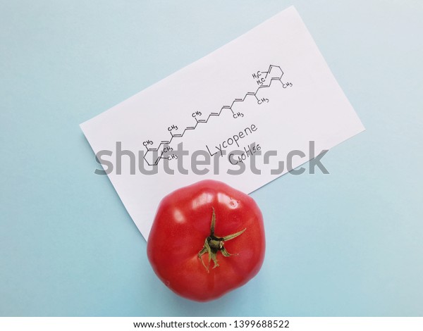 Structural chemical formula of lycopene molecule written on a white sheet of paper with tomato. Lycopene is red tomato pigment molecule.