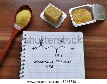 Structural chemical formula of monosodium glutamate (or MSG) with spoonful of a yellow, dry, seasoning spice mix and bouillon cubes. MSG is used in cooking as a flavor enhancer in many food.