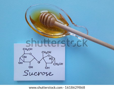 Structural chemical formula of sucrose molecule with a bowl of honey. It is a disaccharide molecule composed of glucose and fructose. Honey gets its sweetness from fructose, glucose, and sucrose.