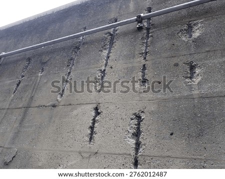 Structural deterioration: Multiple vertical rebar exposures on a concrete wall awaiting repair