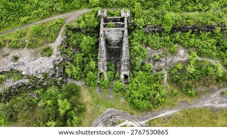A structural edifice that acts as the gateway to a network of underground tunnels surrounded by vibrant green vegetation.