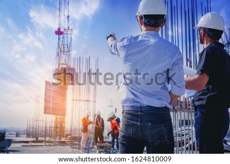 Structural engineer and architect working with blueprints discuss at the outdoors construction site.