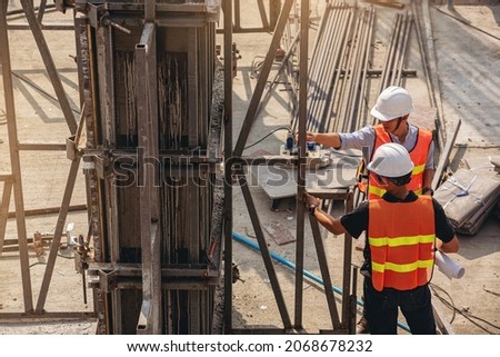 Structural engineer and foreman worker with blueprints discuss, plan inspecting for the outdoors building construction site.