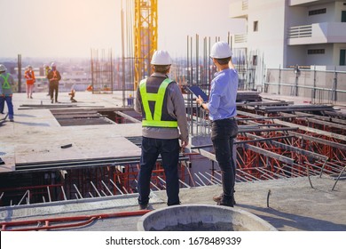Structural engineer and foreman worker with touch pad discuss, plan working for the outdoors building construction site.