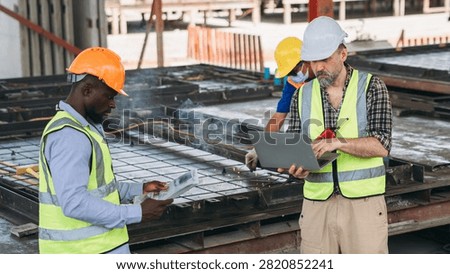 Structural engineer and foreman worker using a digital touch pad to discuss and plan construction workflows at an outdoor building site.