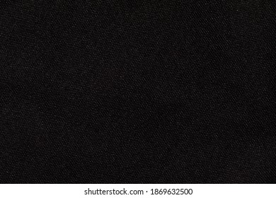 Structure of black fabric as pattern backdrop. Dark grey background from textile material with wicker texture.