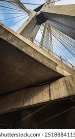Structure of a bridge seen from below. Architecture, cement, cables, from the point of view of someone passing underneath.