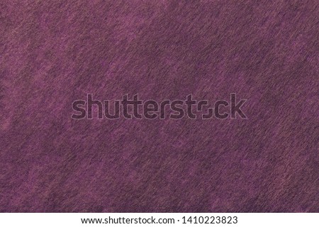 Structure of dark purple background with brown spots of felt fabric, closeup. Texture of woolen magenta matt textile. Cloth backdrop.