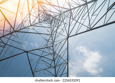 Structure pattern from bottom view of high voltage pole power transmission tower with clear sky sunshine day background light leak effect. Green energy, environmental conservation concept.