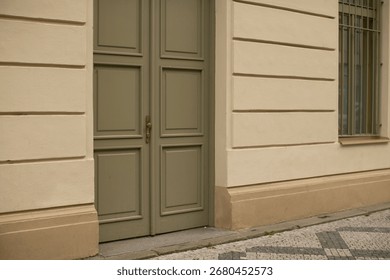 The structure in question is a whitecolored building featuring a distinct green door along with a single window