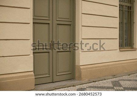The structure in question is a whitecolored building featuring a distinct green door along with a single window