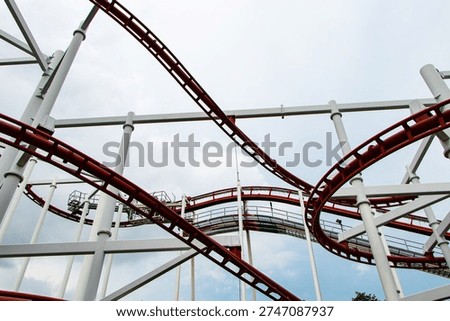 Structure roller coaster track in amusement park with blue sky cloud is background and modern steel. Thrilling roller coaster racing through twists and loops at lively excitement, fun of high speed.