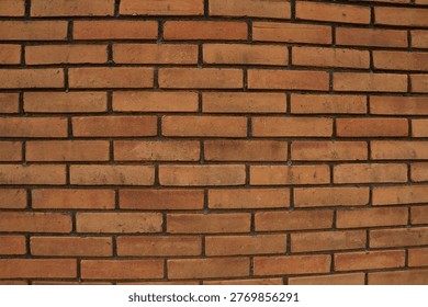 A structured brick wall featuring warm brown and orange tones, with neatly aligned bricks separated by dark mortar lines, creating a classic architectural pattern.