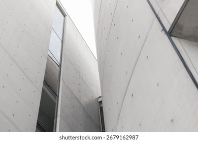 Structures with smooth concrete surfaces create an intriguing interplay of light and shadow. The design highlights angular forms and large glass elements, enhancing the modern aesthetic