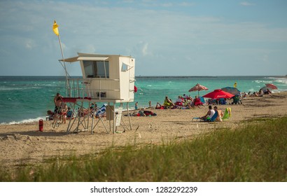 Stuart, Florida, USA - January 1, 2019:Wooden Lifeguard Tower  with Yellow Flag at a Beach. People at a Beach