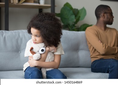 Stubborn African American dad and daughter sit aside back to back on home coach ignore talking after fight, black offended girl hug stuffed toy avoid speak or look at father after quarrel at home - Powered by Shutterstock