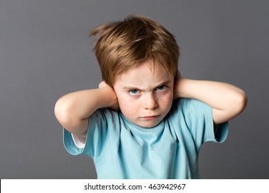 stubborn little kid with red hair, freckles and an attitude ignoring parents scolding, blocking his ears with hands against education problems, grey background