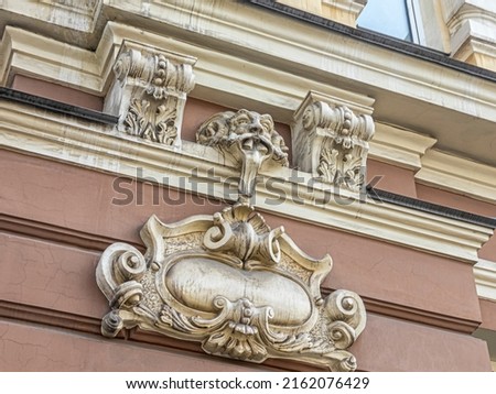 Stucco details and mascaron on the facade of the building in the form of a grotesque faun's head with a long tongue and ram's horns