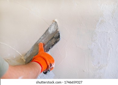 Stucco wall builder. Men's hands plaster the wall. Spatula in the hands of a male stator. Construction work in the house, painting