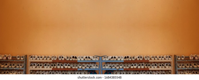 Studant Shoes  On The Rack With Orange Background In Rural School 