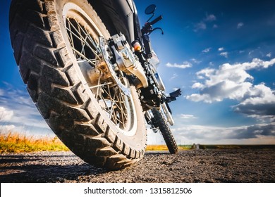 Studded cross motorcycle wheel on the ground level. Focus on the rear wheel. Details of a motorbike closeup. Traveling concept. Driving the empty road on a tour journey. Discover the beauty of earth. - Powered by Shutterstock