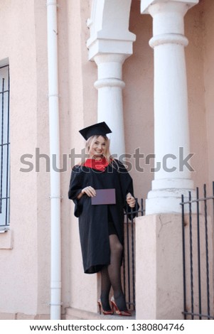 student in academic dress holds a diploma