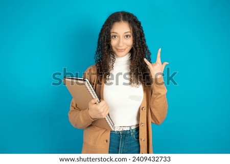 Student arab girl with curly hair makes rock n roll sign looks self confident and cheerful enjoys cool music at party. Body language concept.